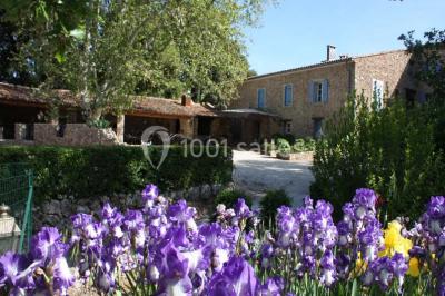 Mobilier de jardin blanc disposé sur une terrasse en gravier, avec vue sur des vignes et une forêt en arrière-plan.
