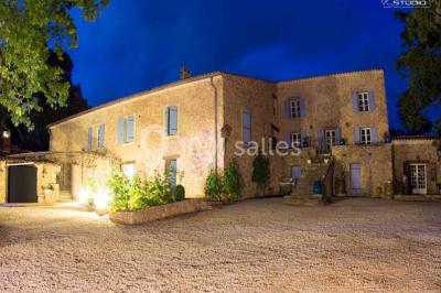 Mobilier de jardin blanc disposé sur une terrasse en gravier, avec vue sur des vignes et une forêt en arrière-plan.