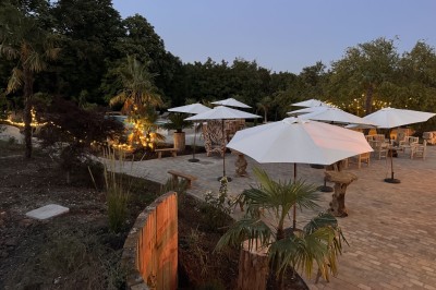 Salle de réception illuminée par des suspensions lumineuses, avec des invités assis à des tables rondes.