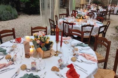 Salle lumineuse avec murs en pierre, tables en bois, poêle à bois et canapé dans un espace chaleureux.