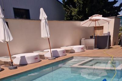 Personnes assises près d'une piscine éclairée, entourées de parasols fermés, avec une enseigne lumineuse ’Vendôme’.