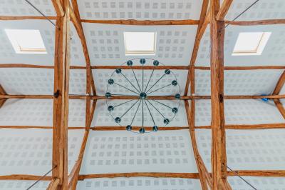 Deux chaises et une table en métal sur une terrasse pavée, près d'une pelouse et d'un bâtiment en pierre.