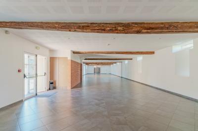 Deux chaises et une table en métal sur une terrasse pavée, près d'une pelouse et d'un bâtiment en pierre.