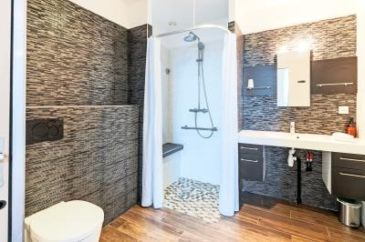 Chambre avec quatre lits superposés, draps à motifs verts, sol en carrelage gris et lumière naturelle provenant d'une…