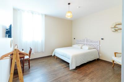 Chambre avec quatre lits superposés, draps à motifs verts, sol en carrelage gris et lumière naturelle provenant d'une…