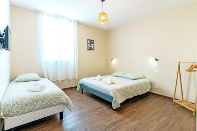 Chambre avec quatre lits superposés, draps à motifs verts, sol en carrelage gris et lumière naturelle provenant d'une…