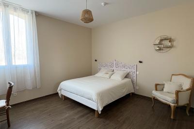 Chambre avec quatre lits superposés, draps à motifs verts, sol en carrelage gris et lumière naturelle provenant d'une…