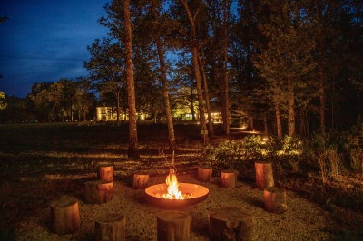 Salle de restaurant lumineuse avec tables dressées, banquettes vertes, chaises blanches et vue sur un jardin arboré.