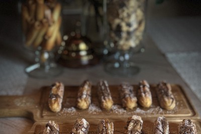 Salle de restaurant lumineuse avec tables dressées, banquettes vertes, chaises blanches et vue sur un jardin arboré.