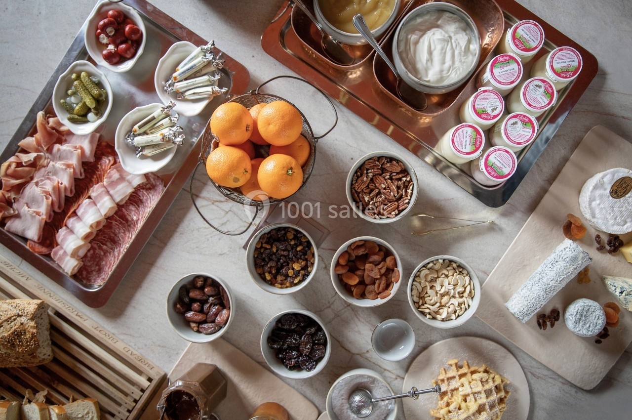 Plateau de petit-déjeuner avec charcuterie, fromages, fruits secs, noix, confitures, miel, oranges et viennoiseries.