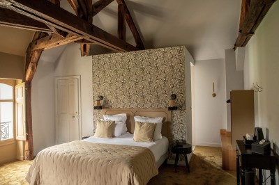 Salle de restaurant lumineuse avec tables dressées, banquettes vertes, chaises blanches et vue sur un jardin arboré.