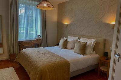 Vue aérienne d'un terrain de tennis rouge entouré de forêt, avec une petite mare et des prairies avoisinantes.