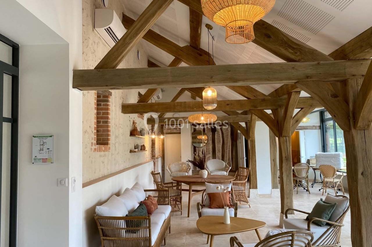 Salle lumineuse avec poutres apparentes, mobilier en rotin et décoration chaleureuse dans un style naturel.