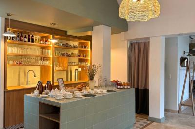 Vue aérienne d'un terrain de tennis rouge entouré de forêt, avec une petite mare et des prairies avoisinantes.