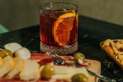 Vue aérienne d'un terrain de tennis rouge entouré de forêt, avec une petite mare et des prairies avoisinantes.