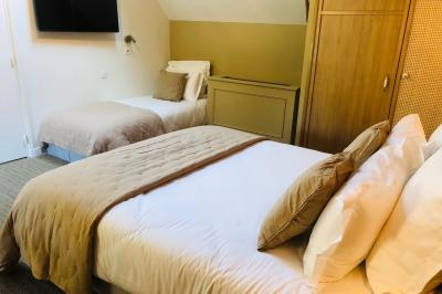 Vue aérienne d'un terrain de tennis rouge entouré de forêt, avec une petite mare et des prairies avoisinantes.