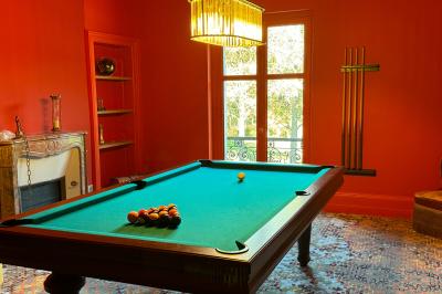 Vue aérienne d'un terrain de tennis rouge entouré de forêt, avec une petite mare et des prairies avoisinantes.