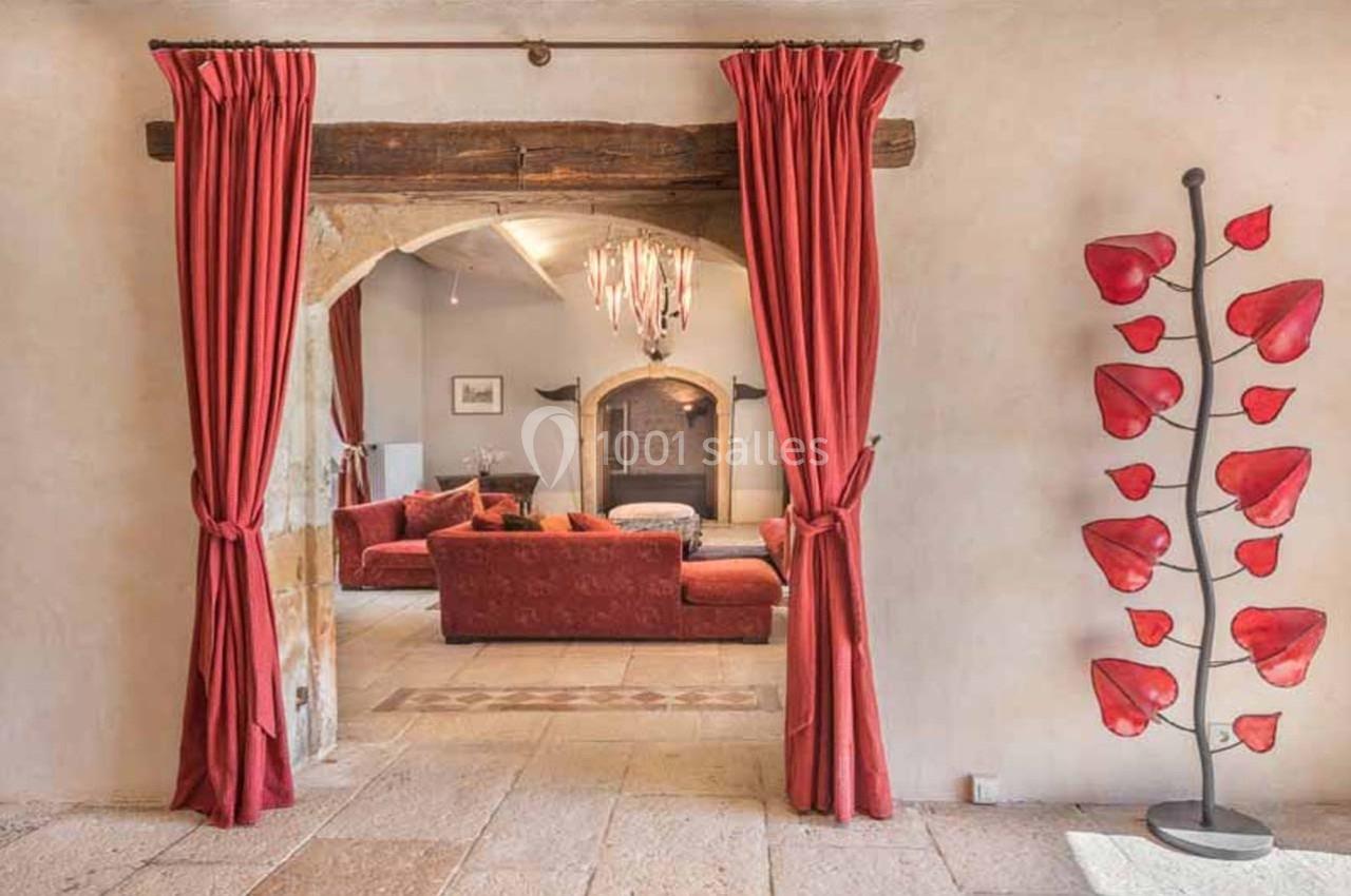 Vue d'un salon chaleureux avec canapé rouge, cheminée, rideaux assortis et sculpture décorative en forme de feuilles rouges.