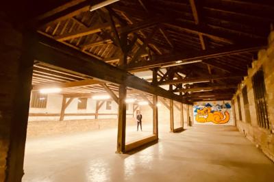 Miniature Location salle Toulouse-le-Château (Jura) - Forges de Baudin #3 Intérieur d'une grande pièce en pierre avec plafond en poutres apparentes, sol en dalles et lumière naturelle.
