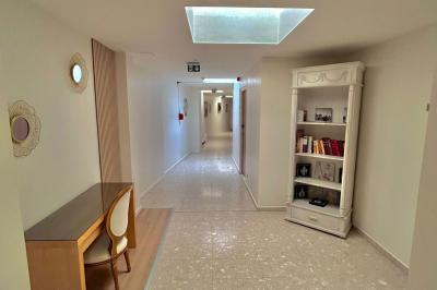 Petit jardin avec une table et des chaises roses, entouré de plantes et d'un puits en pierre devant des maisons.