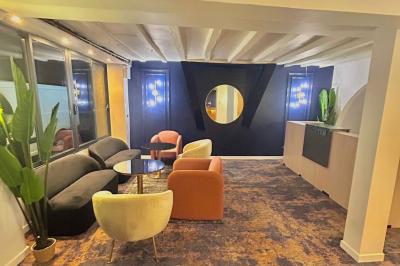 Petit jardin avec une table et des chaises roses, entouré de plantes et d'un puits en pierre devant des maisons.