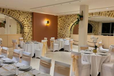Petit jardin avec une table et des chaises roses, entouré de plantes et d'un puits en pierre devant des maisons.