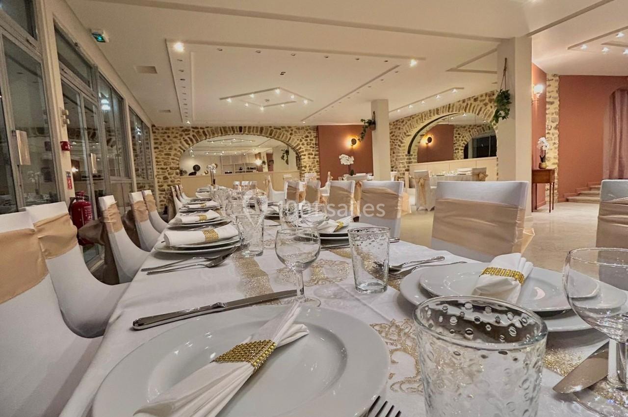 Salle de réception élégamment décorée avec des tables dressées, nappes blanches et détails dorés.