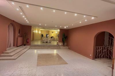 Petit jardin avec une table et des chaises roses, entouré de plantes et d'un puits en pierre devant des maisons.