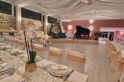 Petit jardin avec une table et des chaises roses, entouré de plantes et d'un puits en pierre devant des maisons.