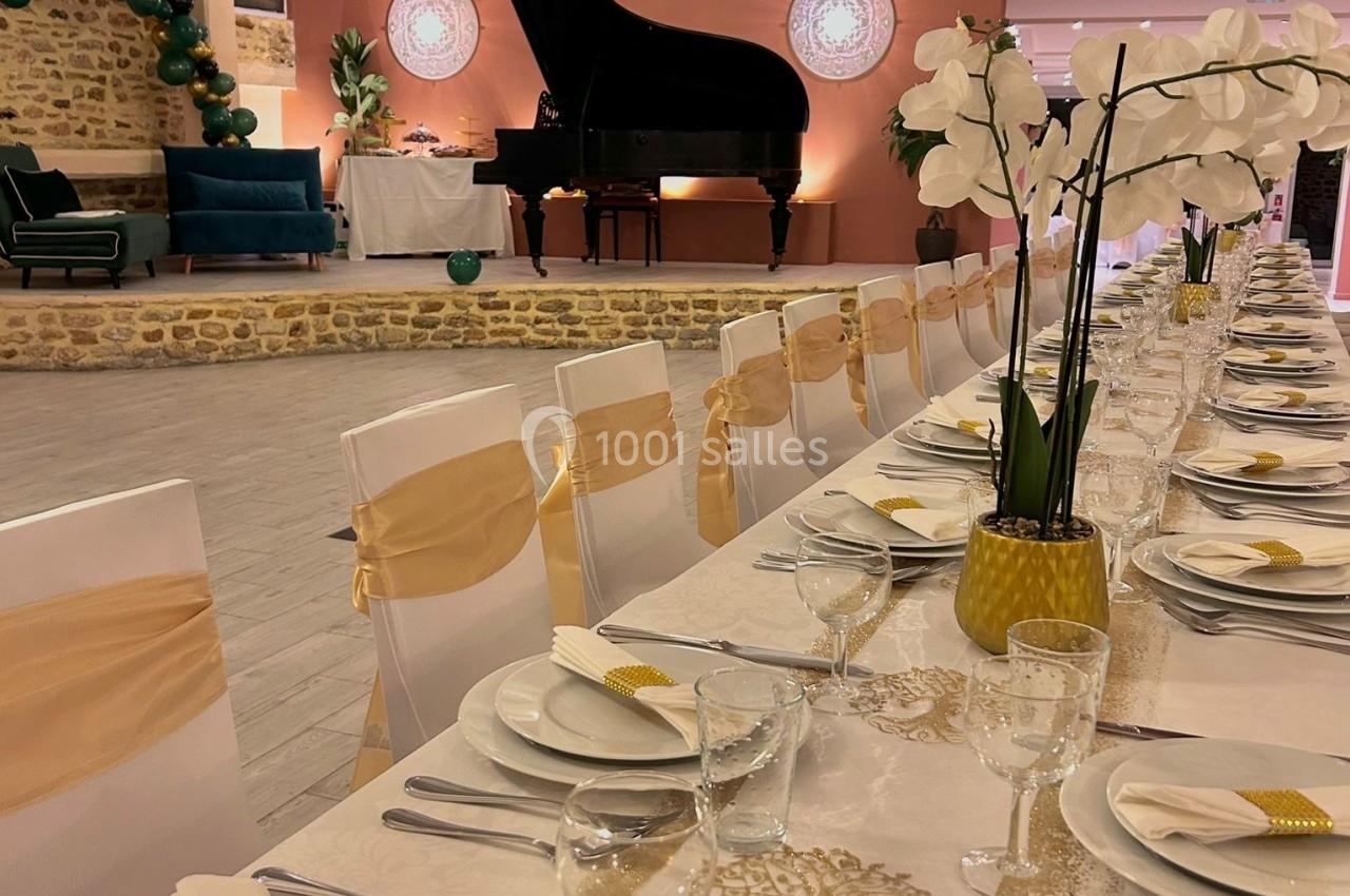 Salle de réception élégante avec une longue table dressée, un piano à queue et une décoration raffinée.