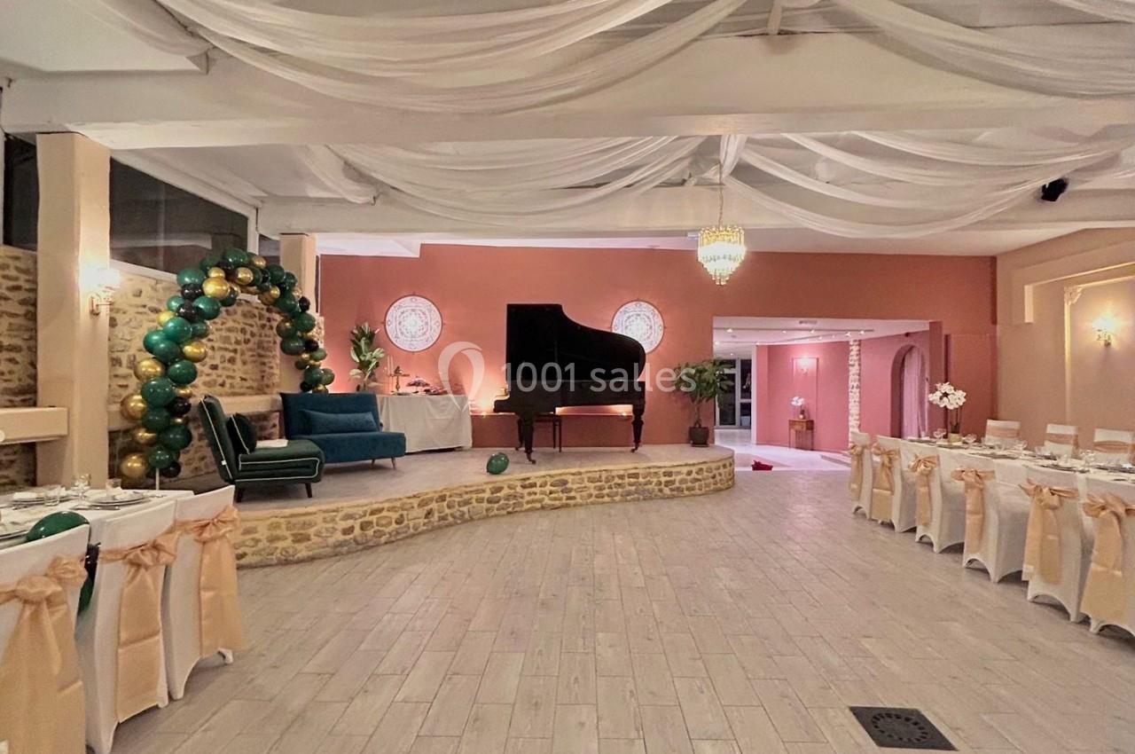 Salle de réception élégante avec piano à queue, tables décorées et plafond orné de drapés blancs.