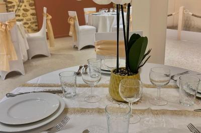 Petit jardin avec une table et des chaises roses, entouré de plantes et d'un puits en pierre devant des maisons.