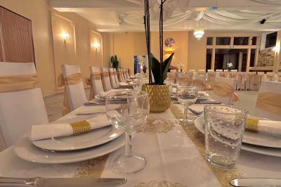 Petit jardin avec une table et des chaises roses, entouré de plantes et d'un puits en pierre devant des maisons.