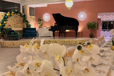 Petit jardin avec une table et des chaises roses, entouré de plantes et d'un puits en pierre devant des maisons.