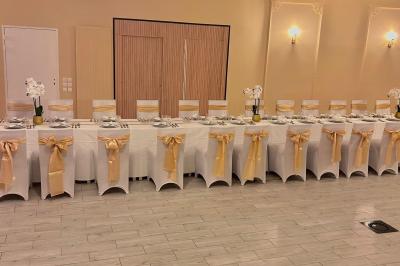 Petit jardin avec une table et des chaises roses, entouré de plantes et d'un puits en pierre devant des maisons.