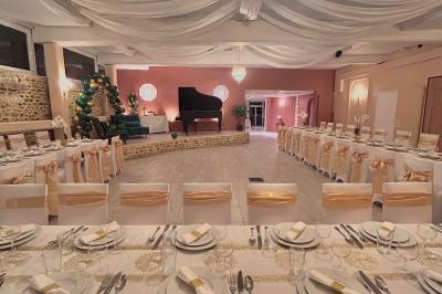 Petit jardin avec une table et des chaises roses, entouré de plantes et d'un puits en pierre devant des maisons.