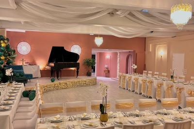 Petit jardin avec une table et des chaises roses, entouré de plantes et d'un puits en pierre devant des maisons.