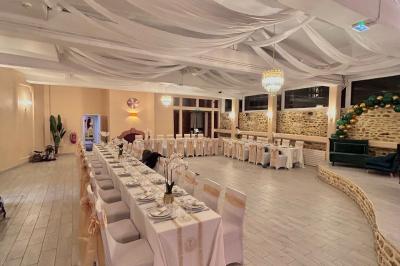 Petit jardin avec une table et des chaises roses, entouré de plantes et d'un puits en pierre devant des maisons.