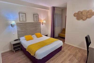 Salle lumineuse avec murs en pierre, mobilier moderne, lampes rouges suspendues et vue sur une entrée vitrée.