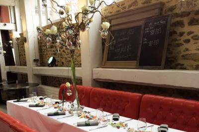 Salle lumineuse avec murs en pierre, mobilier moderne, lampes rouges suspendues et vue sur une entrée vitrée.