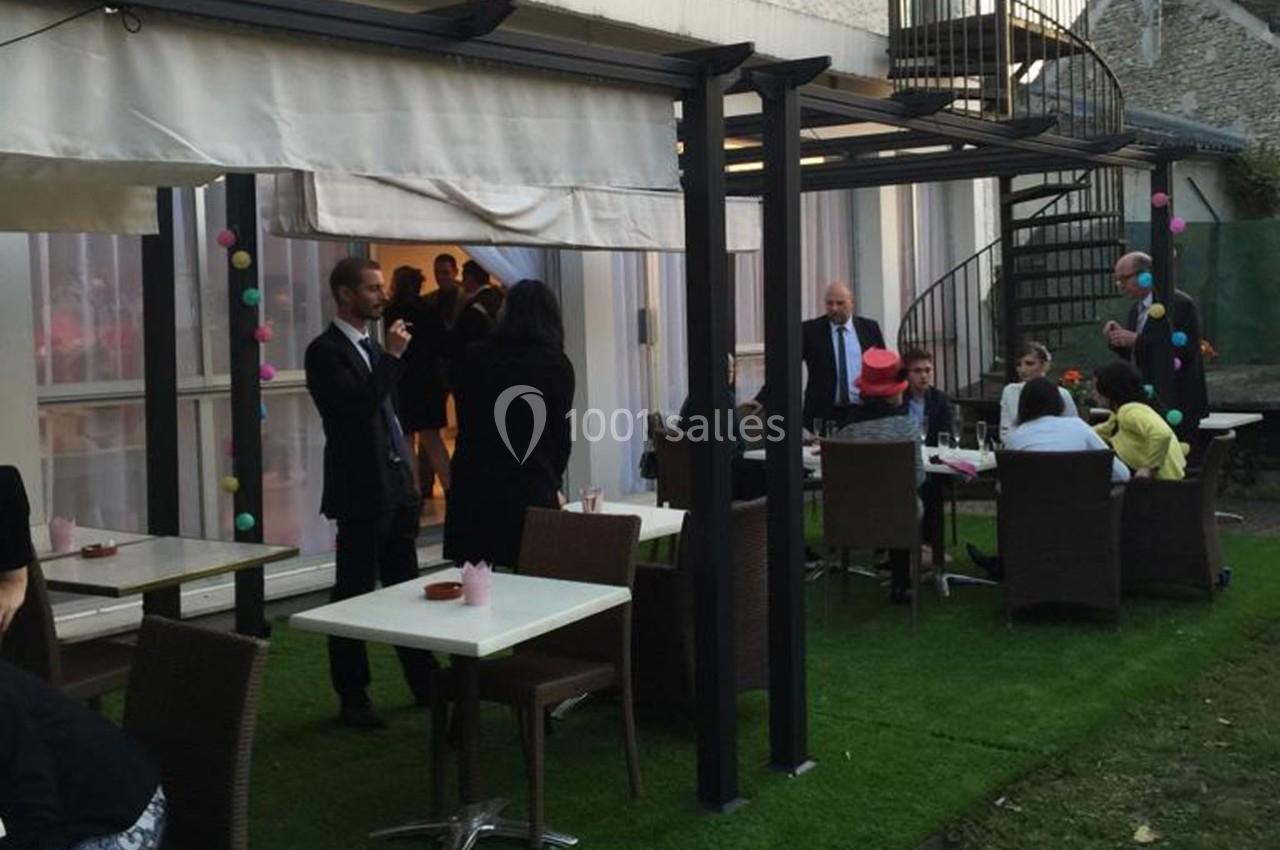 Personnes discutant et partageant un moment convivial sur une terrasse aménagée avec tables et chaises en extérieur.