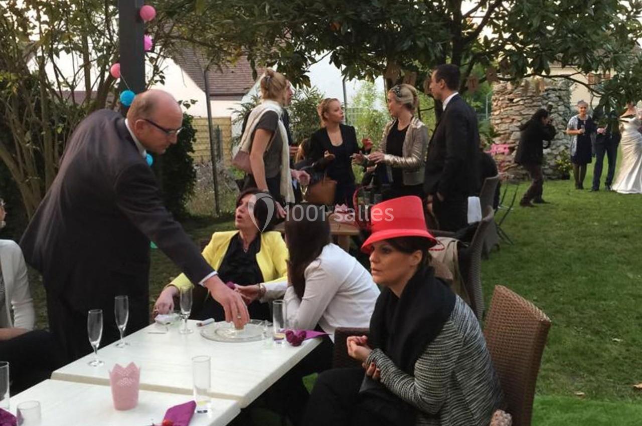 Personnes discutant et partageant un moment convivial dans un jardin lors d'un événement en plein air.