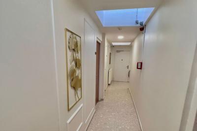 Salle lumineuse avec murs en pierre, mobilier moderne, lampes rouges suspendues et vue sur une entrée vitrée.