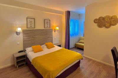 Salle lumineuse avec murs en pierre, mobilier moderne, lampes rouges suspendues et vue sur une entrée vitrée.