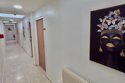 Salle lumineuse avec murs en pierre, mobilier moderne, lampes rouges suspendues et vue sur une entrée vitrée.