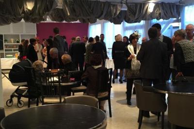 Salle lumineuse avec murs en pierre, mobilier moderne, lampes rouges suspendues et vue sur une entrée vitrée.