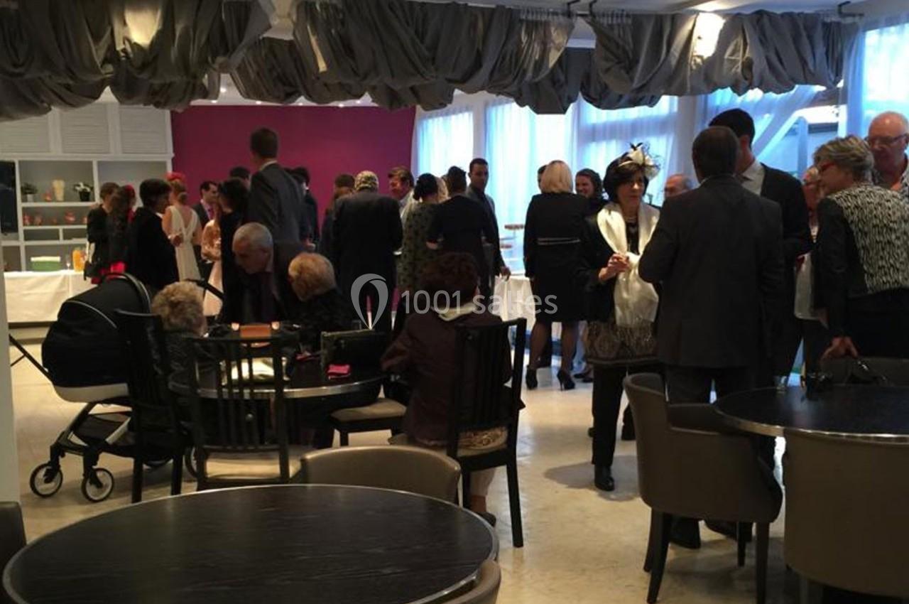 Groupe de personnes debout et assises dans une salle de réception éclairée, discutant autour de tables.
