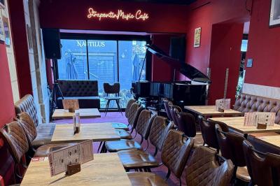 Vue d'un piano à queue dans un restaurant à la décoration chaleureuse avec murs rouges et tables alignées.
