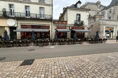 Vue d'un piano à queue dans un restaurant à la décoration chaleureuse avec murs rouges et tables alignées.