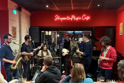 Vue d'un piano à queue dans un restaurant à la décoration chaleureuse avec murs rouges et tables alignées.